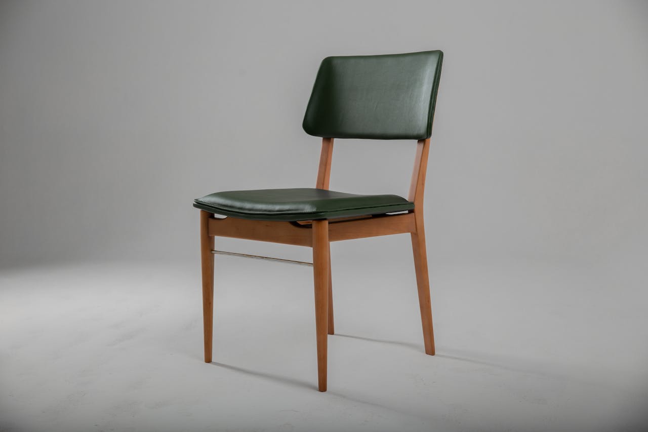 Stylish green leather and wooden chair in a minimalist design setting.