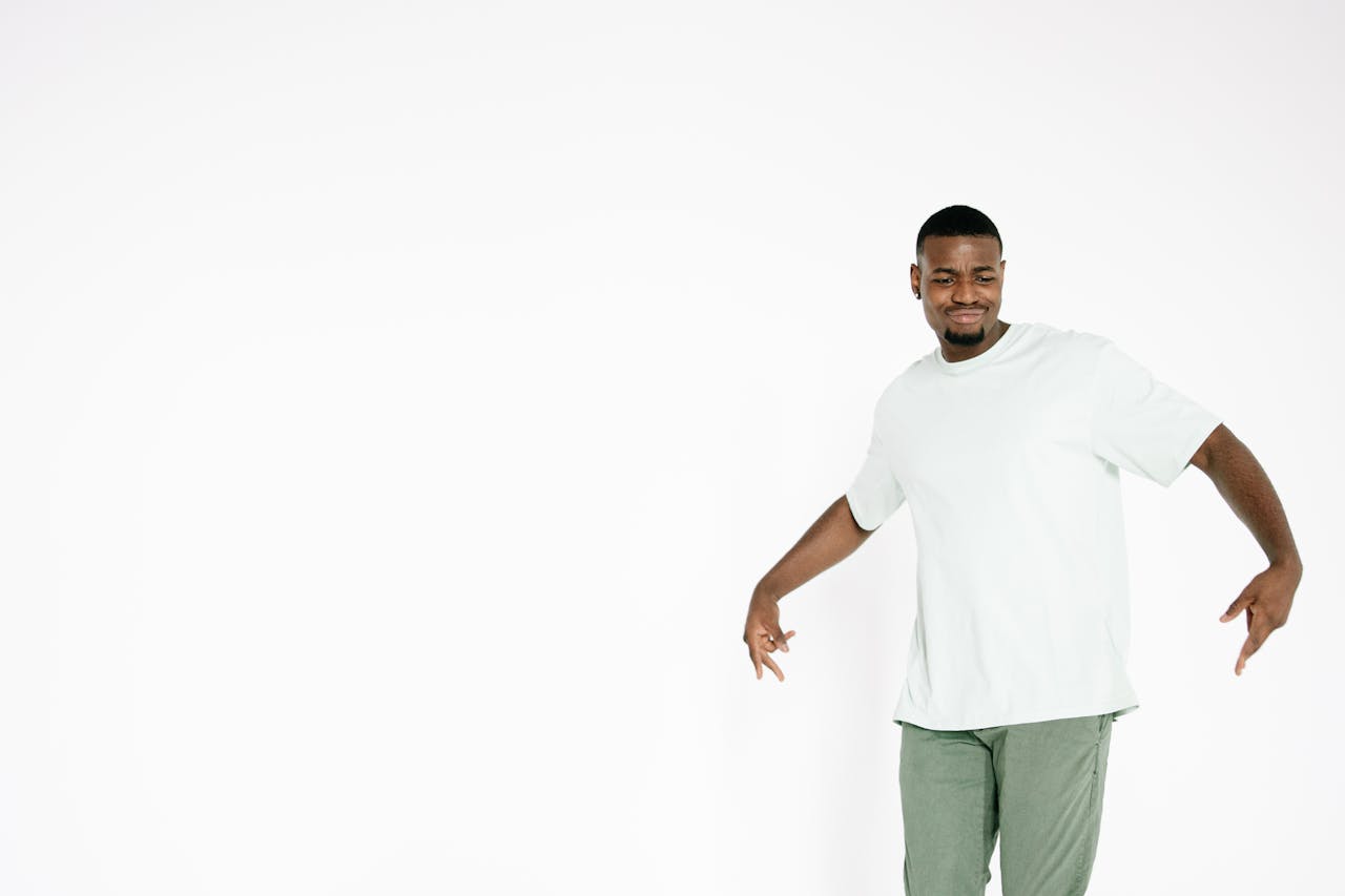 A young black man in a casual pose dancing energetically on a white background.